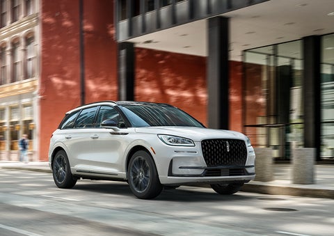 The 2024 Lincoln Corsair® SUV with the Jet Appearance Package and a Pristine White exterior is parked on a city street. | Pilson Lincoln in Mattoon IL